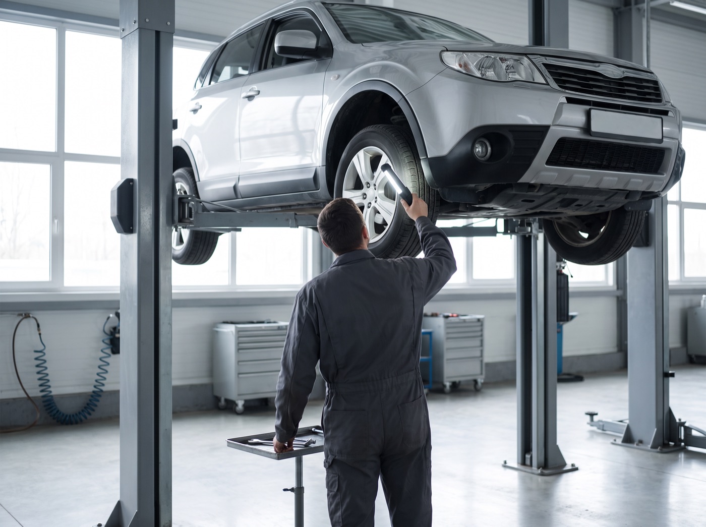 Mechanic inspecting the suspension and brake lines of an SUV on a lift